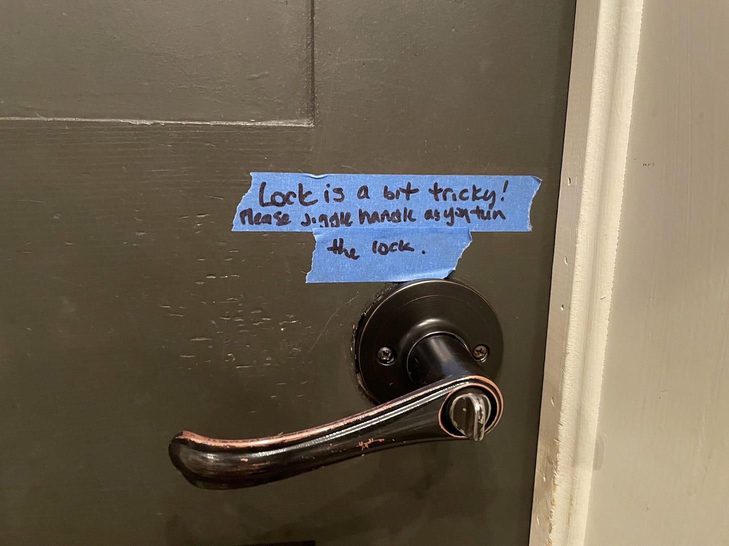 A sign in a washroom about a slightly broken door handle A sign in a washroom about a slightly broken door handle