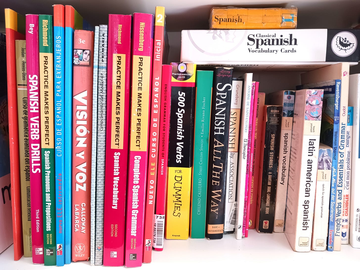 A bookshelf of Spanish textbooks, dictionaries, drill books, flash cards, duel-language short stories, and grammar books.