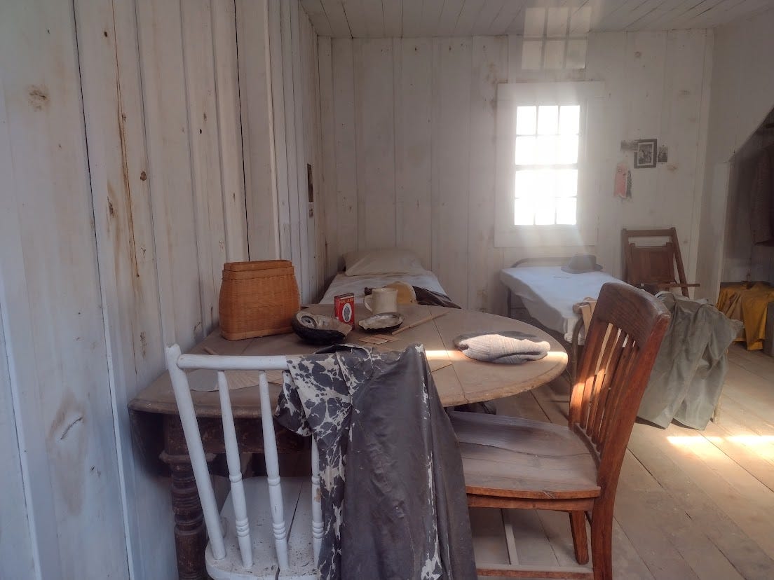 Bare room with twin bed, small table, a few personal items, and chair Bare room with twin bed, small table, a few personal items, and chair