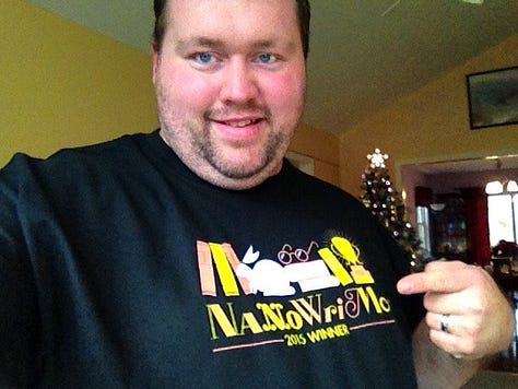 Eric Beaty playing guitar posing with Breedlove and Ibanez guitars wearing a NaNoWriMo winner shirt and posing with Smart Focus book series