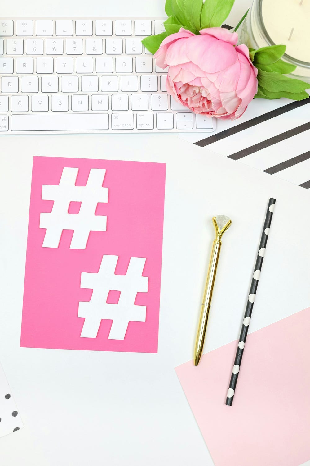 a keyboard, flower, pen and two hashtags cut out on pink paper. a keyboard, flower, pen and two hashtags cut out on pink paper.