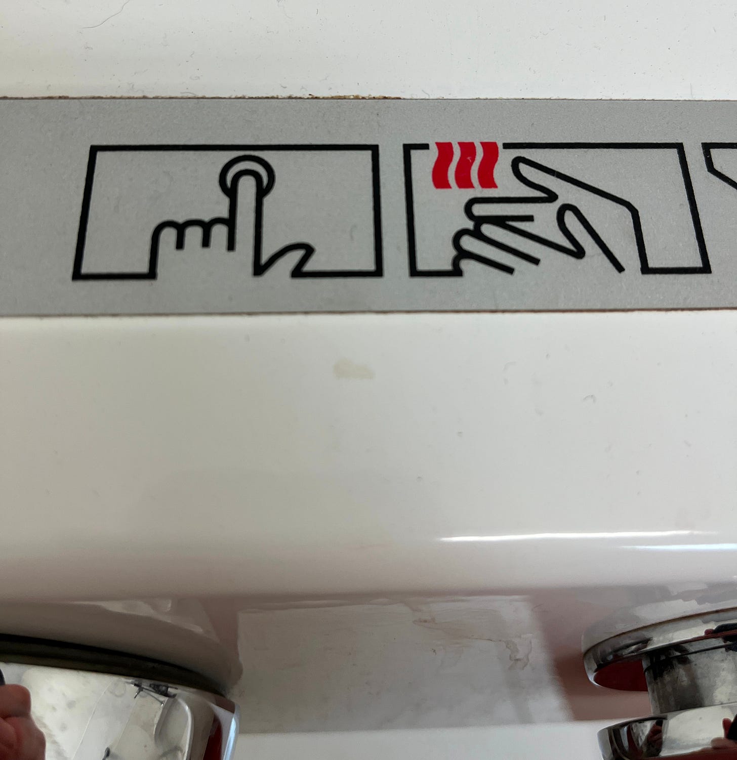 visual instructions for using a hot air drier in a bathoom. the firt image shows a finger touching a butotn. the second indicates heat coming from the drier with three wavy red lines which look suspiciously like bacon. visual instructions for using a hot air drier in a bathoom. the firt image shows a finger touching a butotn. the second indicates heat coming from the drier with three wavy red lines which look suspiciously like bacon.