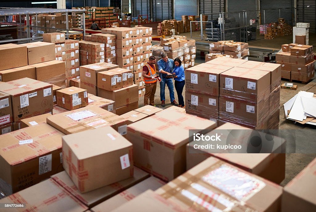 Looking for a specific item Shot of people at work in a large warehouse full of boxes Warehouse Stock Photo Looking for a specific item Shot of people at work in a large warehouse full of boxes Warehouse Stock Photo