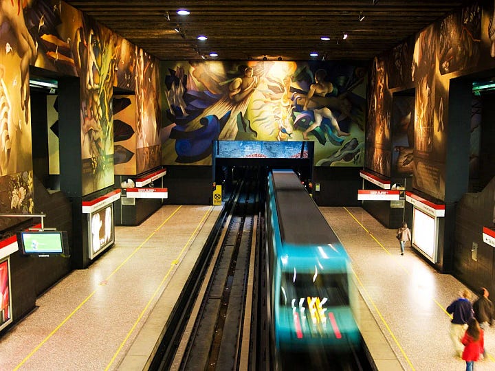 A four-image collage showing ornate and immersive metro stations around the world, including blue painted escalator walls, patterned vaulted ceilings, tiled station interiors, and a train platform with decorative lighting.