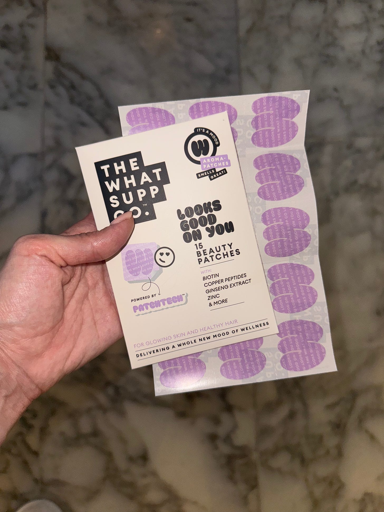 Hand holding The What Supp Co packet of Looks Good On You Patches