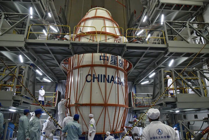The Long March 3B/E's booster and fairing being prepared for the mission, and the ChinaSat-9C satellite being hoisted toward the top of the vehicle.
