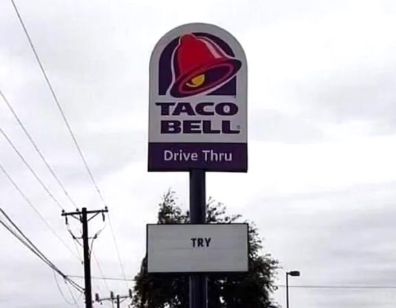 A Taco Bell sign set against a cloudy sky that reads "TRY" A Taco Bell sign set against a cloudy sky that reads "TRY"