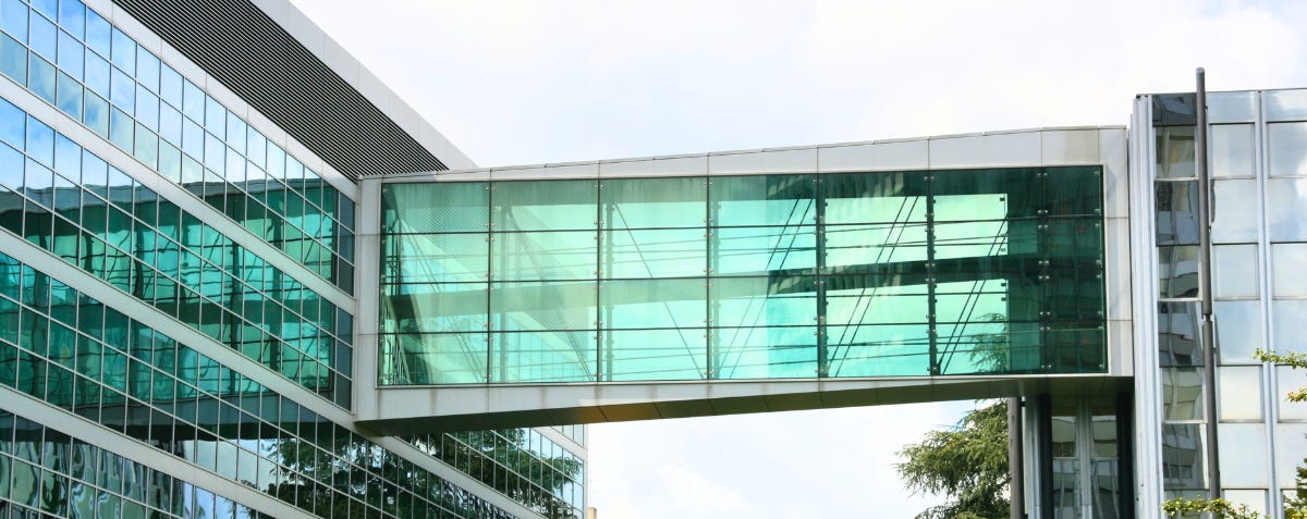 Skybridge (or skyway) connecting the WIPO headquarters buildings in Geneva, CH. A metaphor for bridges connecting separate platfoms. Photo credit: Marek Ślusarczyk. Image modified or fit and color. CC BY 3.0. Skybridge is used here as a metaphor for connections between separate platforms.