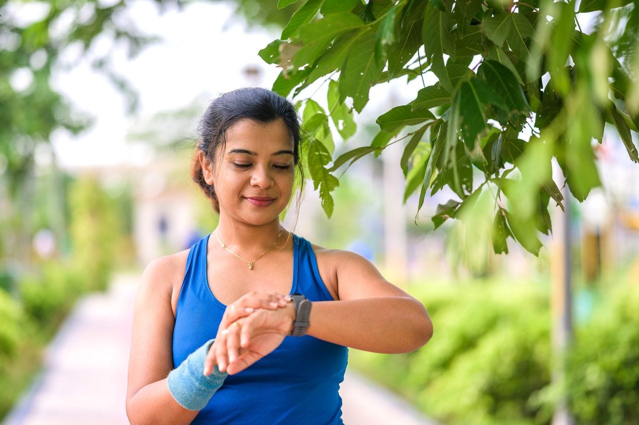Woman checking her fitness watch on an outdoor walk Woman checking her fitness watch on an outdoor walk