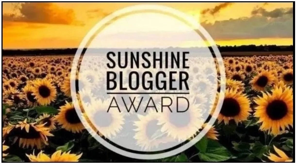Logo of SUNSHINE BLOGGER AWARD in a frosty-white circle, surrounded by a sunflower farm at sunset