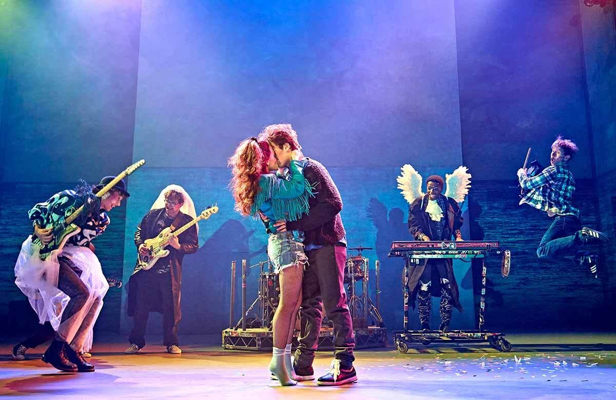 Conor and Raphina kiss while the band plays behind them.