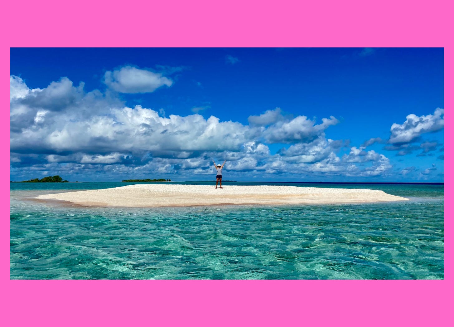 Woman standing on a sandbar surrounded by crystal blue seas