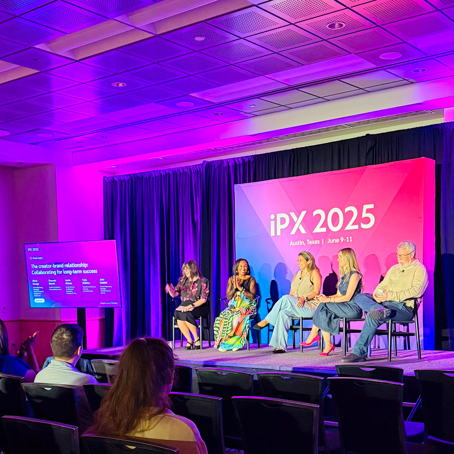 Shaunda Necole speaking on a creator-brand relationship panel at iPX 2025 in Austin, Texas, seated onstage alongside fellow industry experts. The brightly lit conference backdrop highlights the event’s branding and the engaged audience.