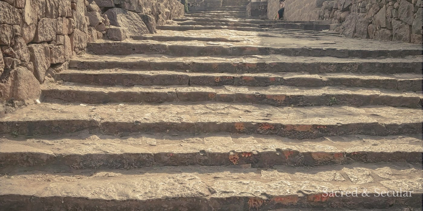 Worn stone steps leading upward between old walls, showing signs of age and gradual erosion.