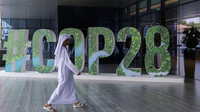 Someone walking past a physical sign that says #COP28 Someone walking past a physical sign that says #COP28