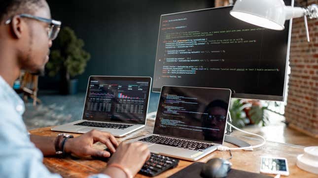 person coding on multiple computers