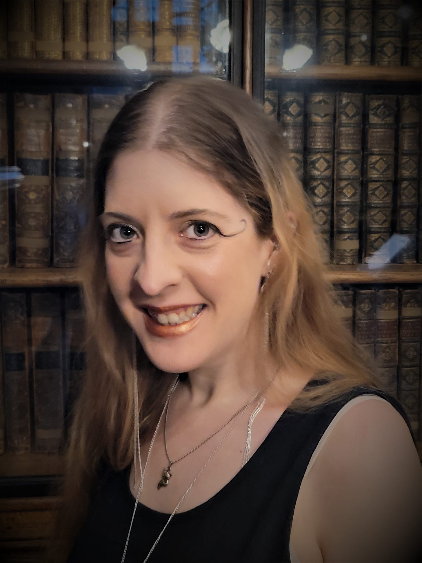 A portrait of Alethea Lyons, in front of a bookcase. 
