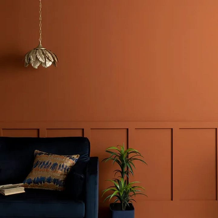 butterscotch painted walls with navy sofa and gold light pendant