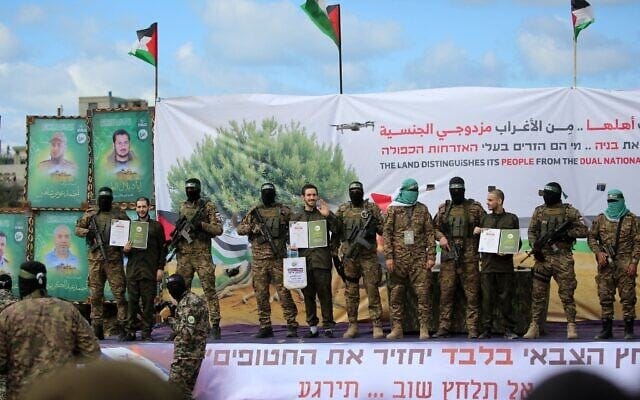 Eliya Cohen (left), Omer Shem Tov (center) and Omer Wenkert, flanked by armed fighters, on stage at a Hamas propaganda ceremony for their release in Gaza on February 22, 2025 (Eyad BABA / AFP)
