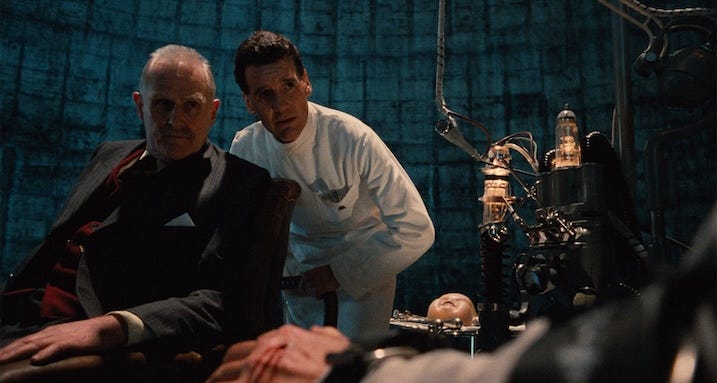 Interrogation still — Michael Palin’s Jack Lint and Peter Vaughan’s Helpmann preside over a chilling torture scene in Brazil (1985).