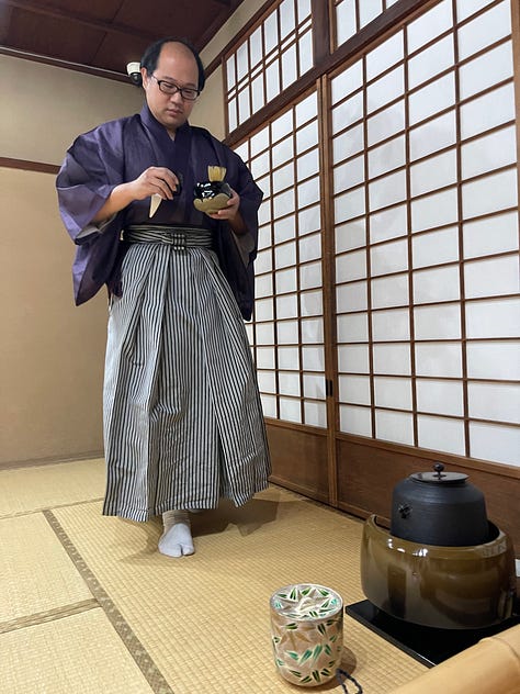 A collage of nine photos from Japan: a man in traditional kimono performing a tea ceremony; a tray of delicate kaiseki dishes with seasonal ingredients; a serene temple garden surrounded by moss and trees; a tatami room with sliding shoji doors; a mountain view with Mount Fuji in the distance; a bowl of Japanese dessert with green grapes and jelly; a Shinto wedding procession under a red umbrella; a moss-covered stone Buddha statue in a forest; and misty temple grounds framed by lush greenery.