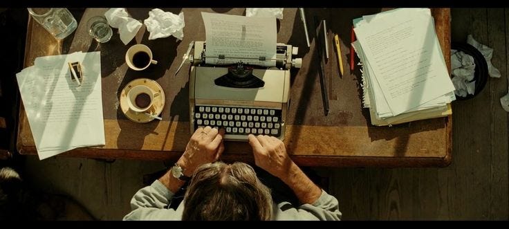 This may contain: a person sitting at a desk with an old fashioned typewriter