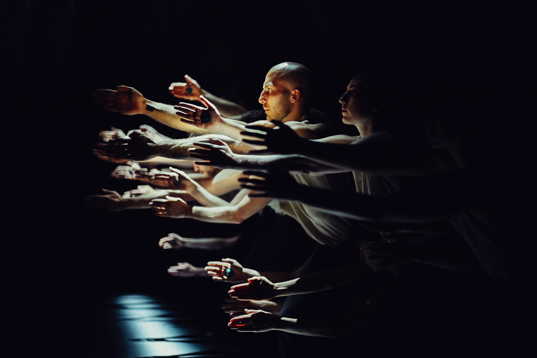 A photo showing dancers hands lit so they look like a shoal of fish