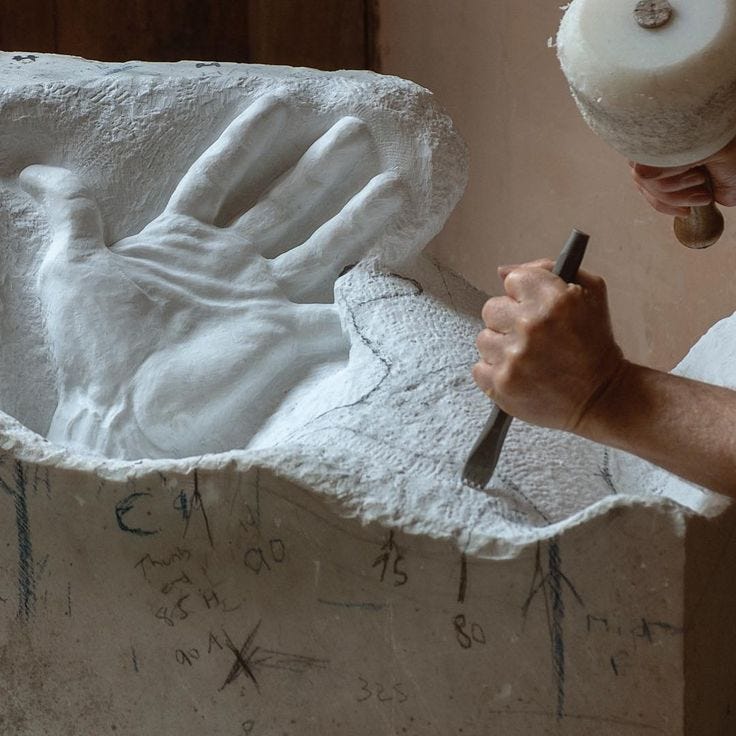 A sculptor chiseling a marble statue, shaping and refining the stone to reveal the form within, illustrating the process of developing ideas through writing.