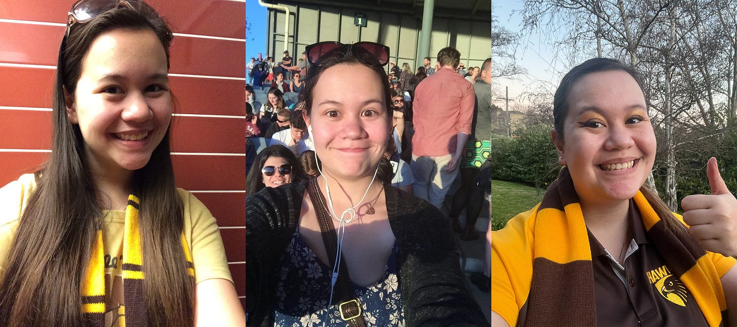 From left to right, this image shows three photographs of Julia. She is a woman with long brown hair and she is older in each photo. The first one was taken on the morning of the AFLM Grand Final 2015 and she's wearing a Hawks t-shirt and scarf. The middle one was taken at the first ever AFLW game in 2017 and she is wearing a blue floral dress, grey cardigan, sunglasses and wired headphones. She looks annoyed because she's just found out that her friends have been locked out. The third photograph shows her on the day of the first every Hawthorn AFLW game wearing a Hawks shirt and scarf. She's wearing matching brown and gold eye make-up, smiling and holding her hand in a thumbs up. From left to right, this image shows three photographs of Julia. She is a woman with long brown hair and she is older in each photo. The first one was taken on the morning of the AFLM Grand Final 2015 and she's wearing a Hawks t-shirt and scarf. The middle one was taken at the first ever AFLW game in 2017 and she is wearing a blue floral dress, grey cardigan, sunglasses and wired headphones. She looks annoyed because she's just found out that her friends have been locked out. The third photograph shows her on the day of the first every Hawthorn AFLW game wearing a Hawks shirt and scarf. She's wearing matching brown and gold eye make-up, smiling and holding her hand in a thumbs up.