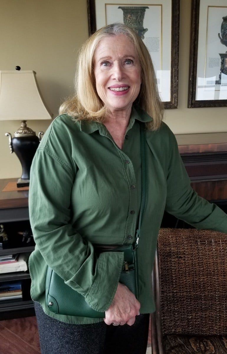Jobie Stern, a senior woman with blonde hair, stands in a room and wears a green jacket. Jobie Stern, a senior woman with blonde hair, stands in a room and wears a green jacket.