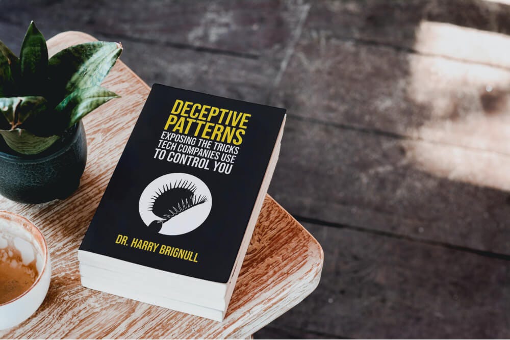 The book "Deceptive Patterns" by Harry Brignull, on a coffee table.