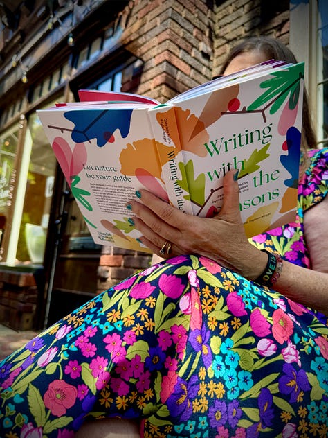 A person wearing a colorful floral dress sitting outdoors, reading an open copy of Writing With The Seasons showing an Emily Dickinson quote on a bright pink page. The back of the journal and A close-up view of a person holding open Writing With The Seasons, displaying the vibrant, leaf-patterned front and back cover.