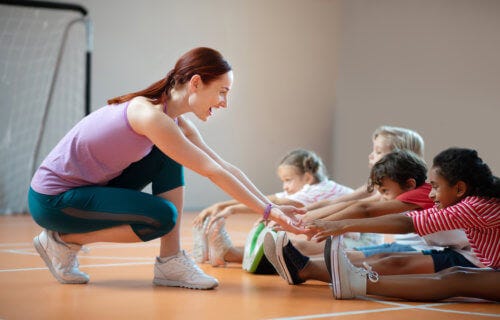 PE teacher having students stretch in gym class
