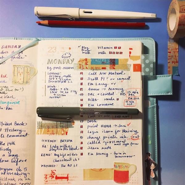 A planner open to a decorated page with pens, colored pencil and washi tape A planner open to a decorated page with pens, colored pencil and washi tape