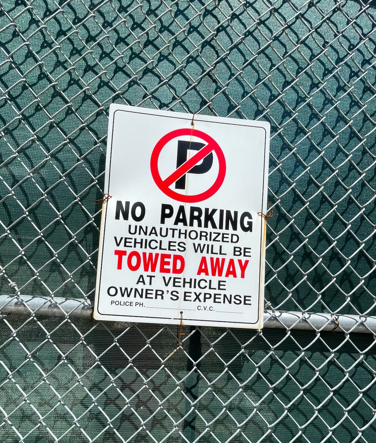 A sign on a fence warning cars not to park here, otherwise they will be towed