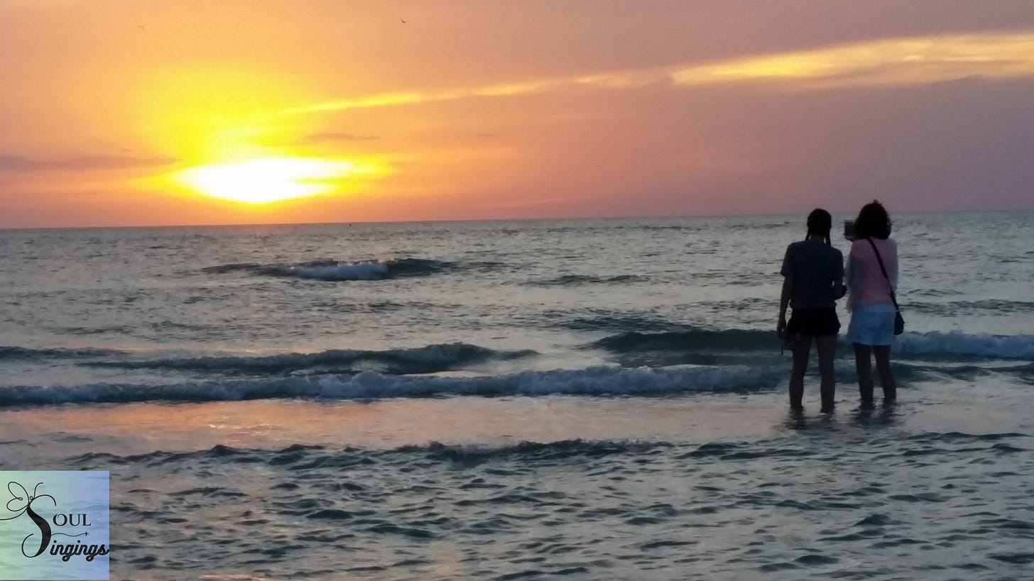 60 Things I've Learned at 60: picture of two women taking pictures of an orange and yellow sunset at the beach