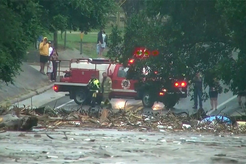 First responders assess floodwaters and debris near a firetruck.
