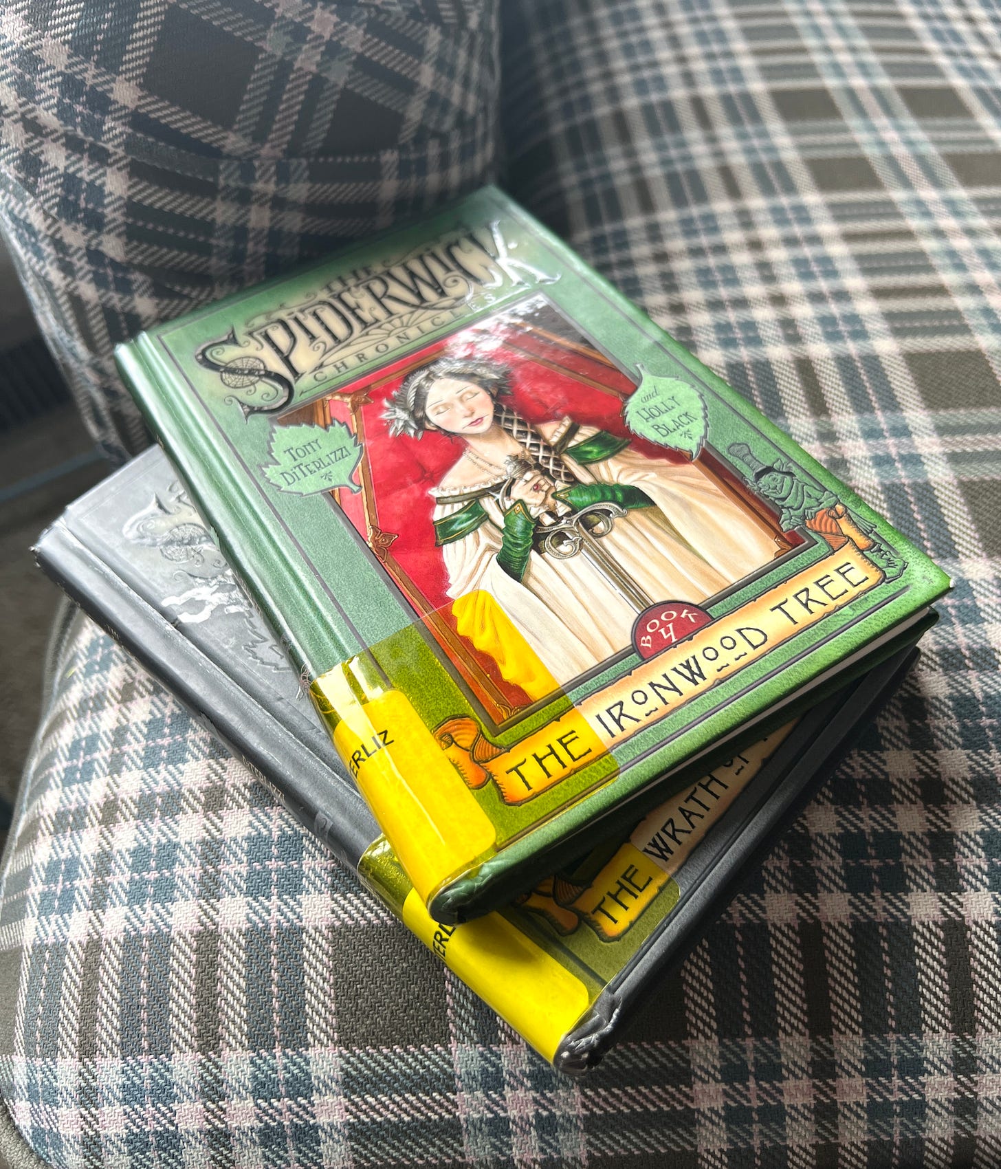 Books 4 and 5 of the Spiderwick Chronicles stacked on the side of an armchair. 