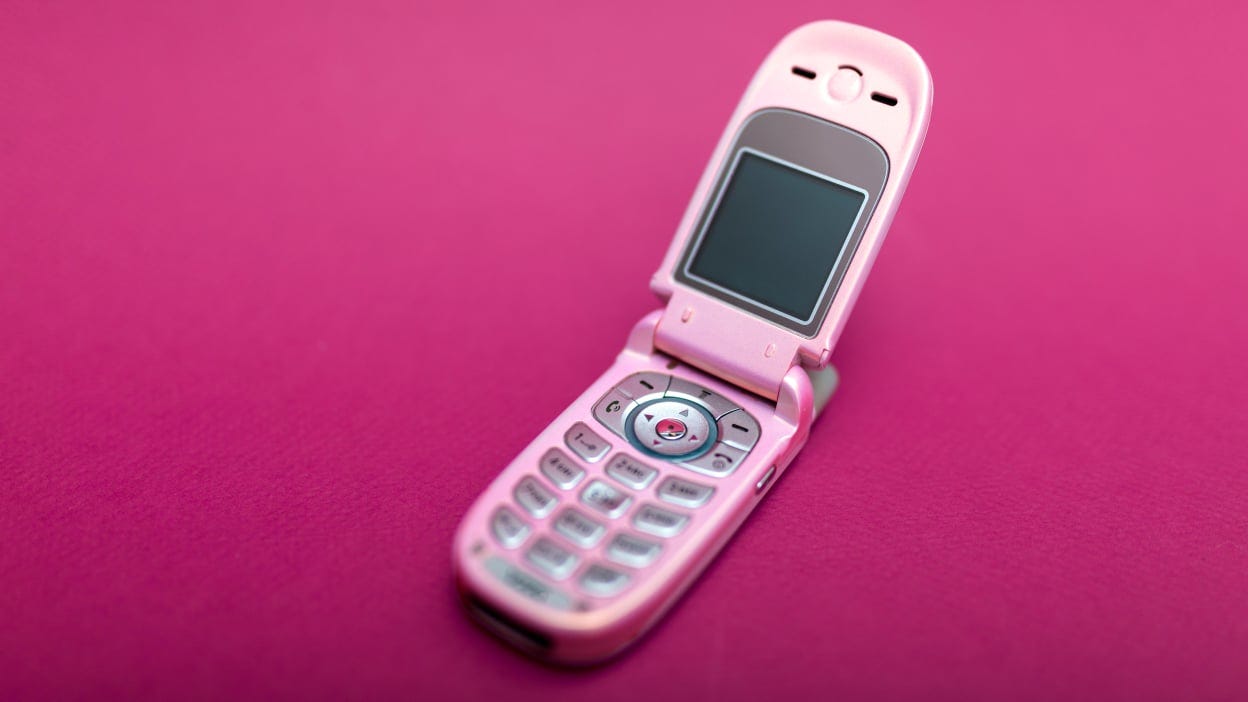 An open flip phone on a magenta background.