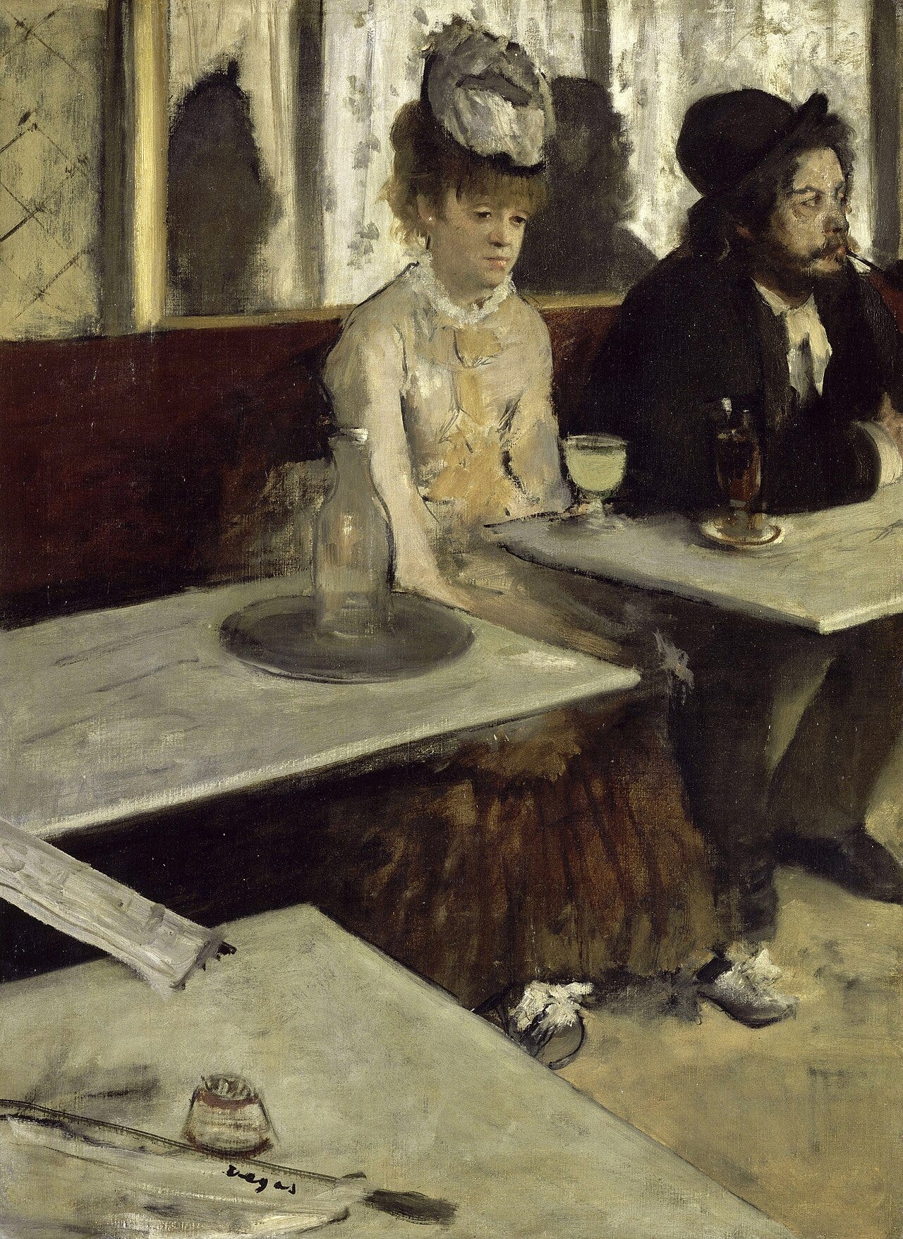 A woman slumped before a glass of absinthe in a cafe
