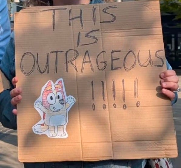 The author holds a Bluey-themed protest sign outsside of KOMO studios in Seattle.