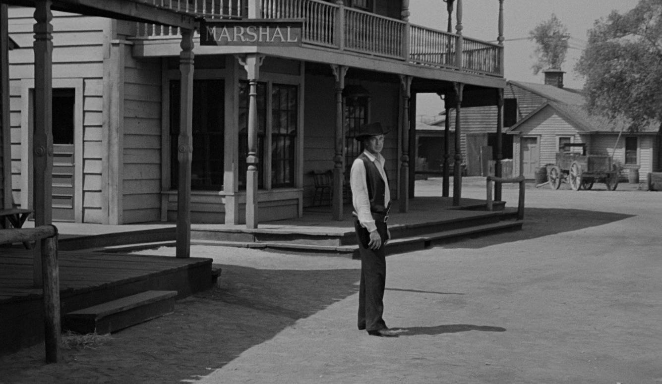 Gary Cooper as Marshal Will Kane stands alone in a dusty Western street outside the marshal's office in High Noon (1952). Gary Cooper as Marshal Will Kane stands alone in a dusty Western street outside the marshal's office in High Noon (1952).