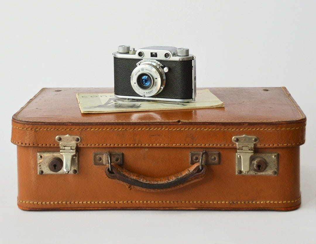 a camera sitting on top of a brown suitcase