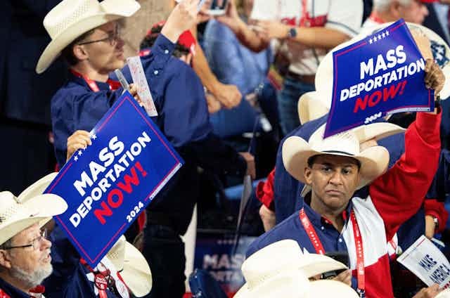Men in cowboy hats in a crowd holding 'Mass deportation now' signs.