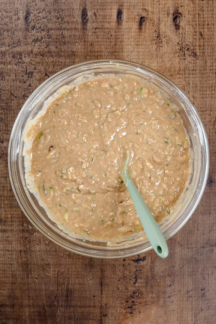 Two images of zucchini bread batter, one in a glass bowl with a green spatula and the other with the batter in a prepared loaf pan lined with parchment paper.