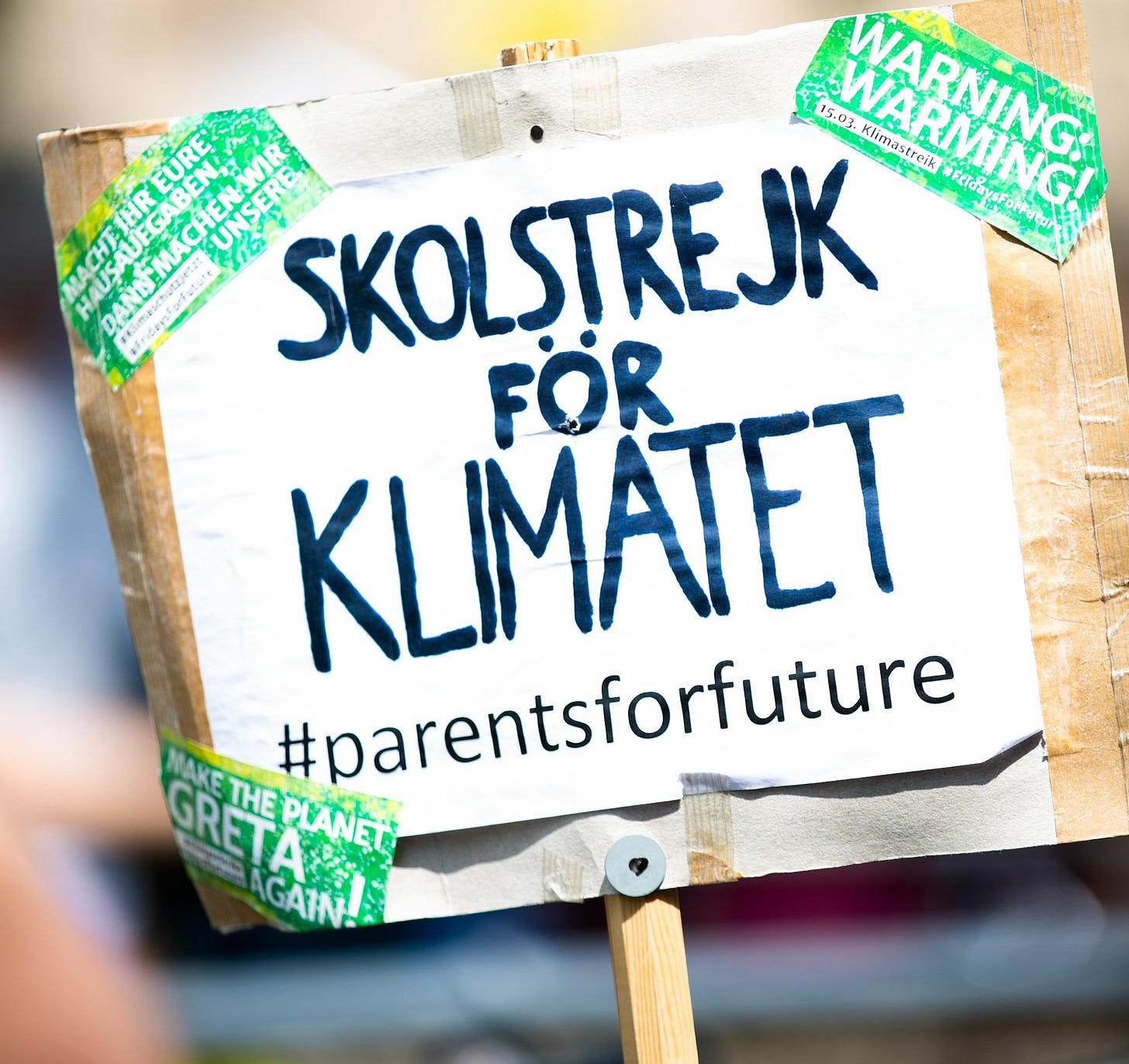 Protest sign reading "SKOLSTREJK FÖR KLIMATET" with hashtag "#parentsforfuture" and green stickers. Protest sign reading "SKOLSTREJK FÖR KLIMATET" with hashtag "#parentsforfuture" and green stickers.