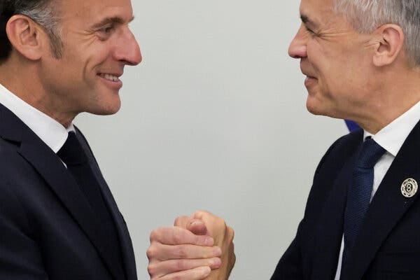 President Emmanuel Macron and Mark Carney clasp hands. 