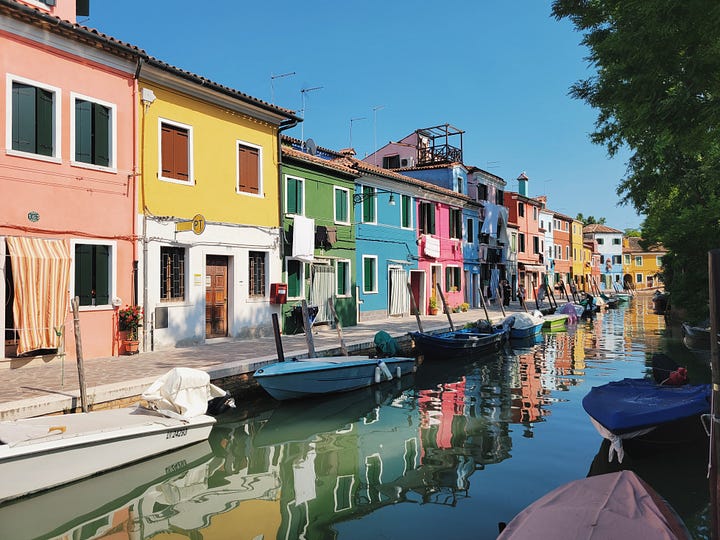 Two views of Burano: colorful houses reflected in a canal lined with boats, and a stone footbridge framed by pink and turquoise buildings