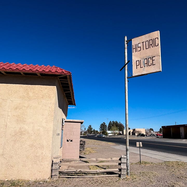 Coral colored cement building with Mexican Restaurant sign and adobe building with Historic Place sign