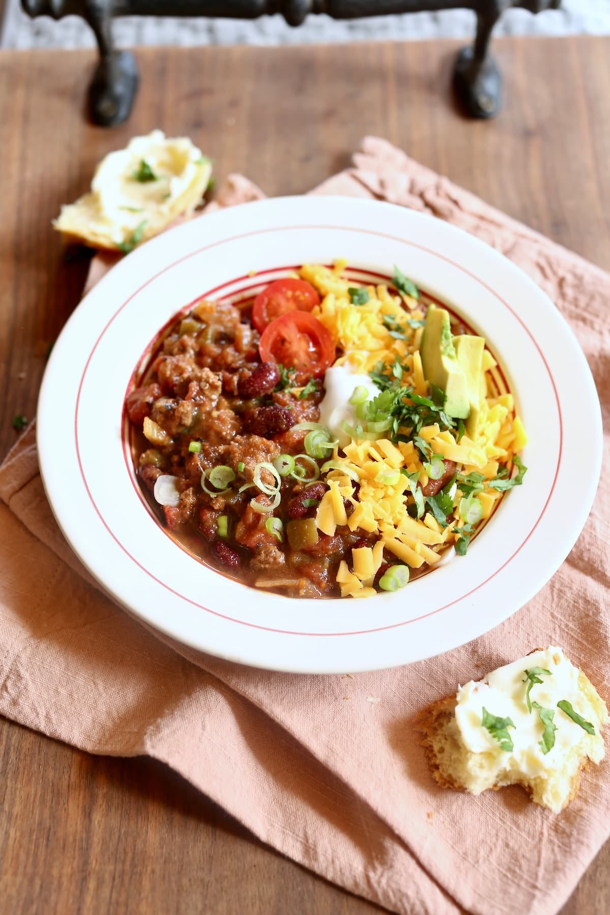 a white bowl of chili with all the fixings on a table.